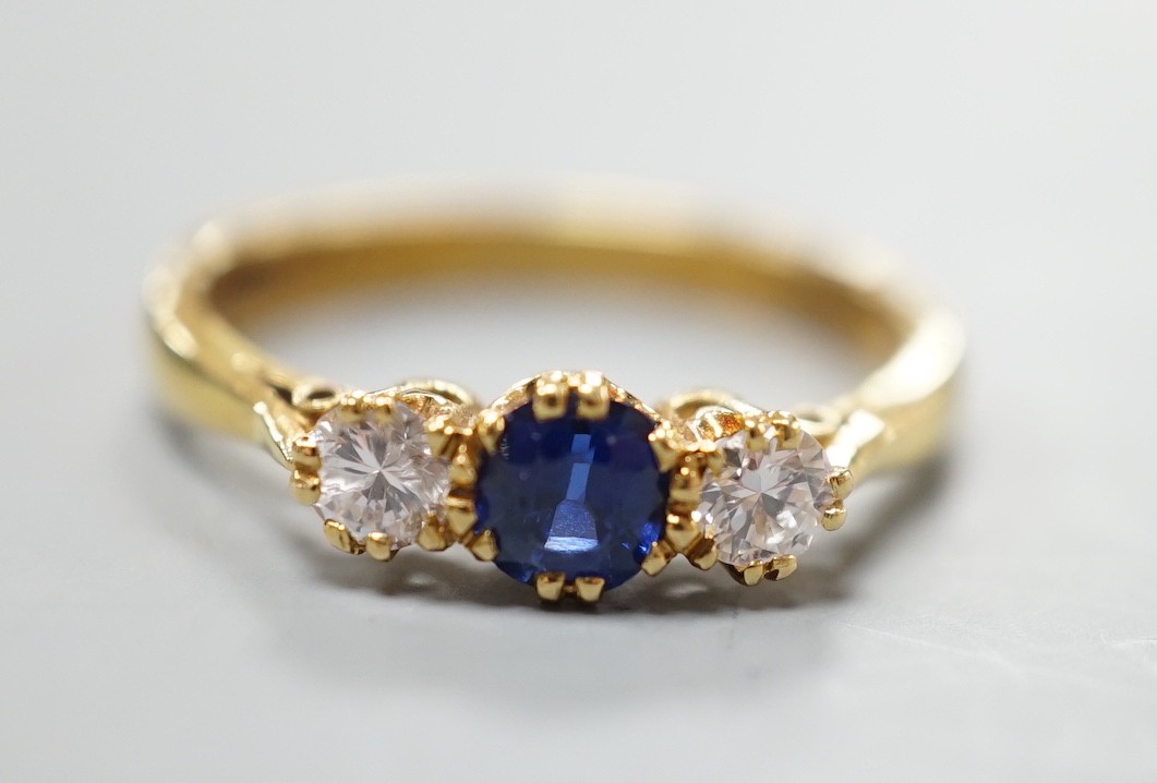A modern 18ct gold, sapphire and diamond set three stone ring, size S, gross weight 4.4 grams